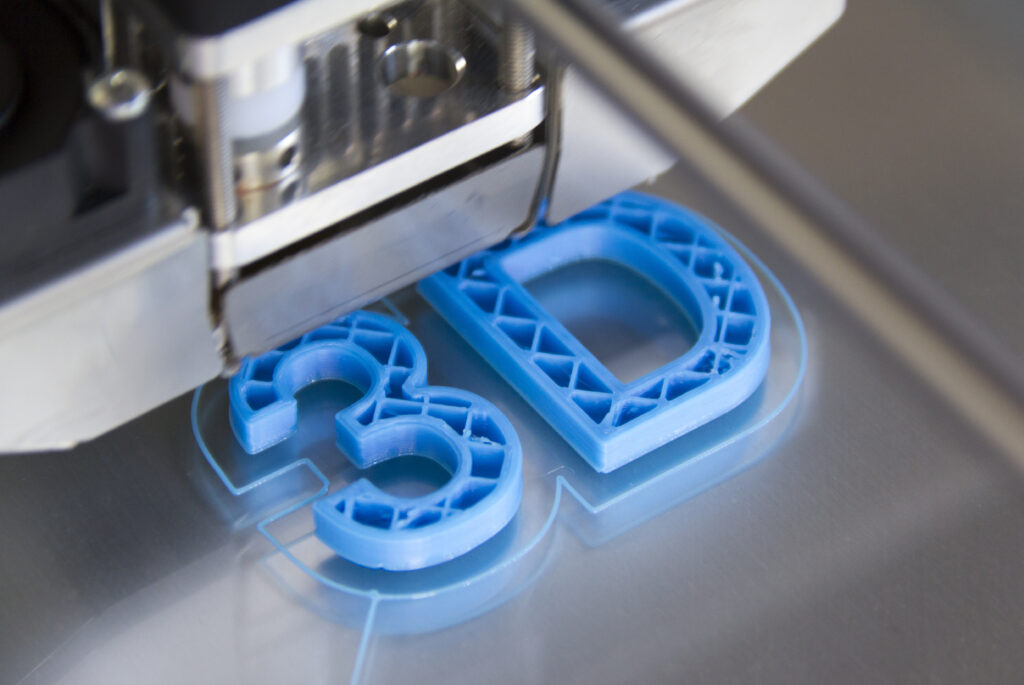 Light blue '3D' number and letter printed out by a 3D printing machine