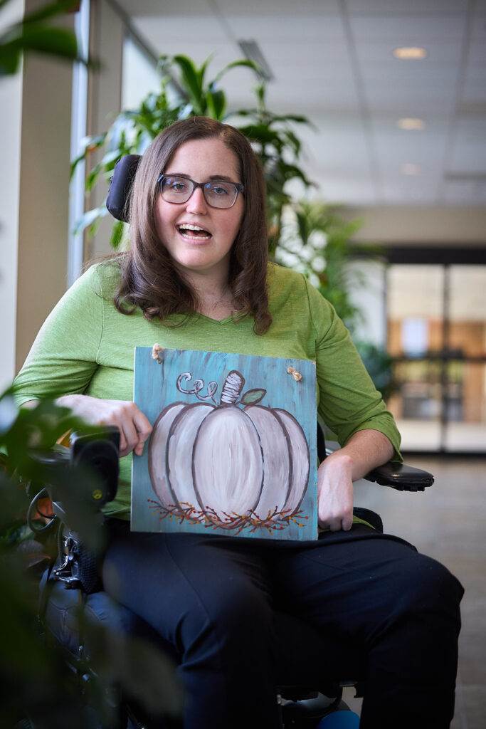 Emily Brong holds a painting of a pumpkin that she painted.